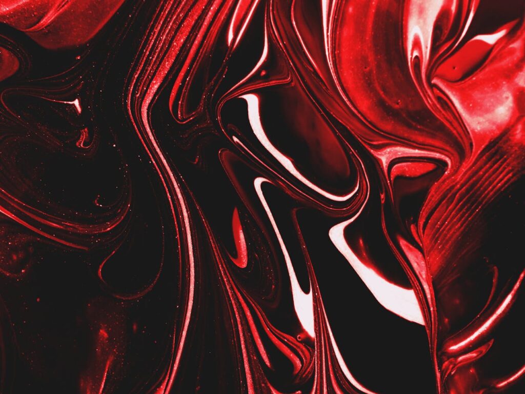 Dynamic swirls of red and black create a striking abstract pattern in acrylic paint.