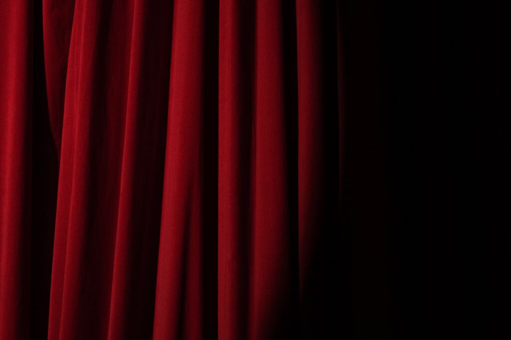 Elegant red velvet curtain with dramatic lighting perfect for theater themes.