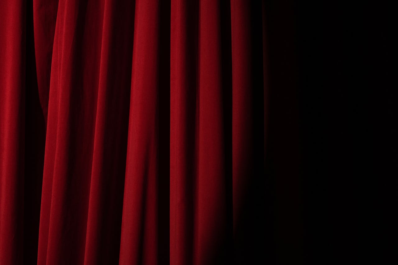 Elegant red velvet curtain with dramatic lighting perfect for theater themes.